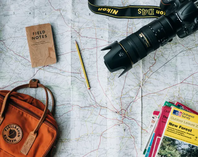 A map, a notebook and a camera laid out to plan a trip